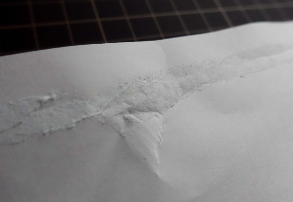 ドットライナーの粘着力を表した画像です。張り付けた所をのりが乾いたあとに剥がすと紙がやぶれるほどです。